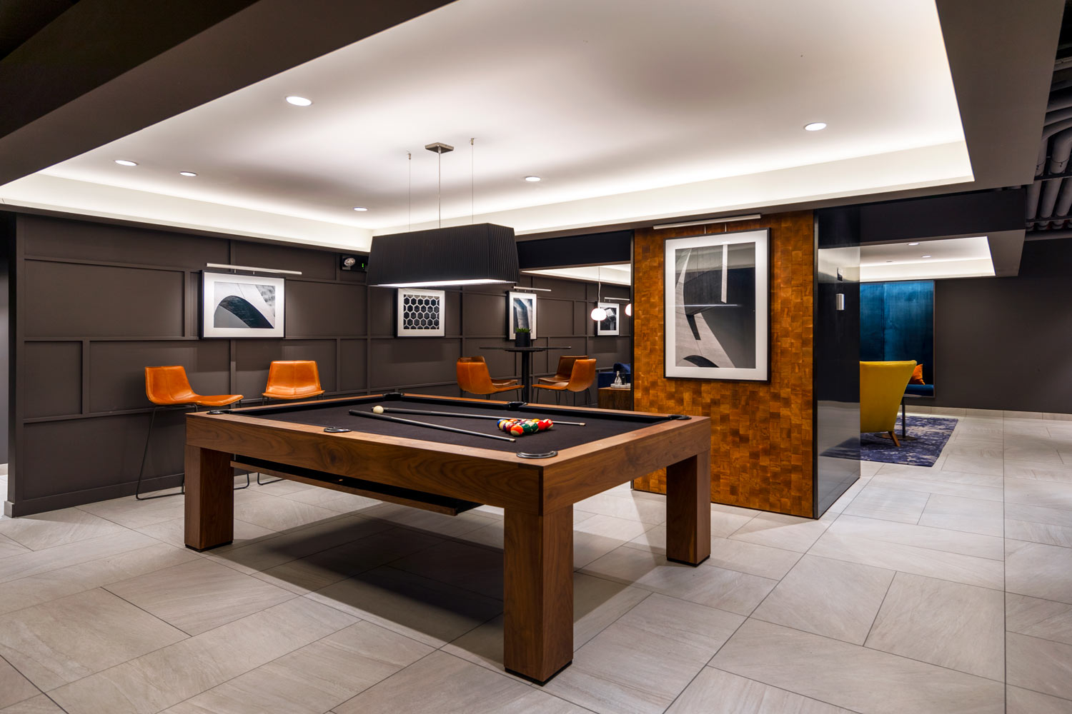 Game lounge with black felt pool table and marble floors, black walls, and art deco wood detailing
