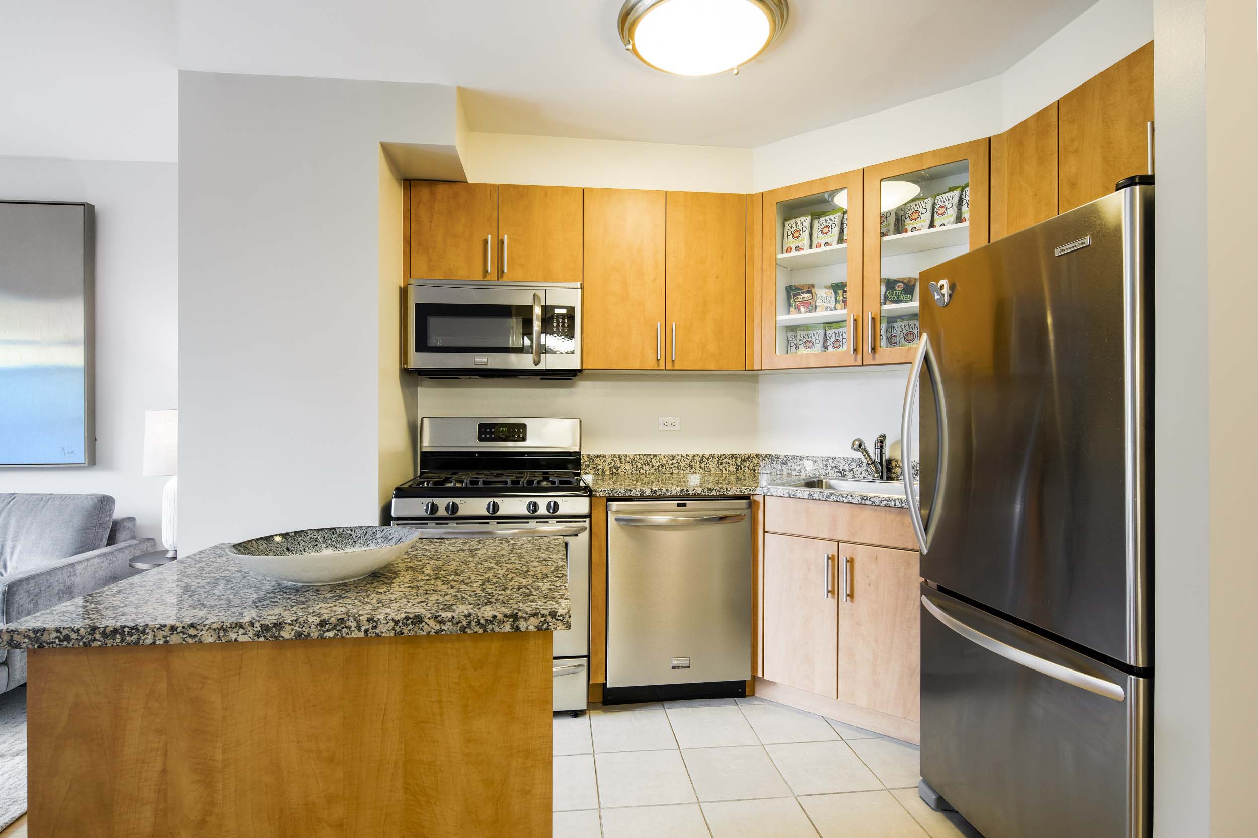 Kitchen with granite top center island and stainless steel dishwasher, stove and refrigerator